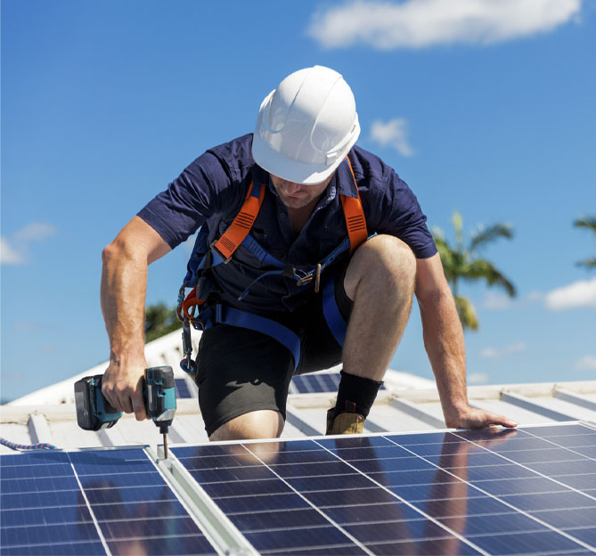 Man working on solar panels on top of a house